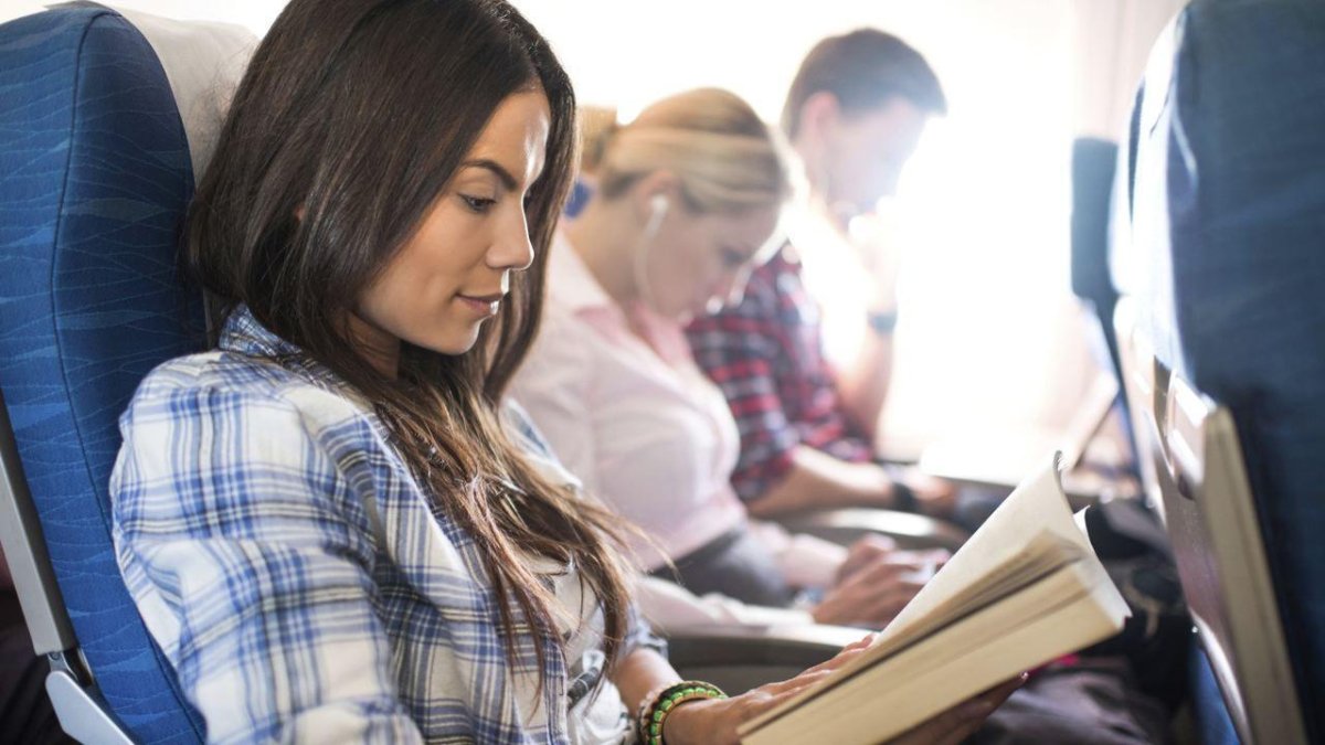 Женщина читает в самолете
