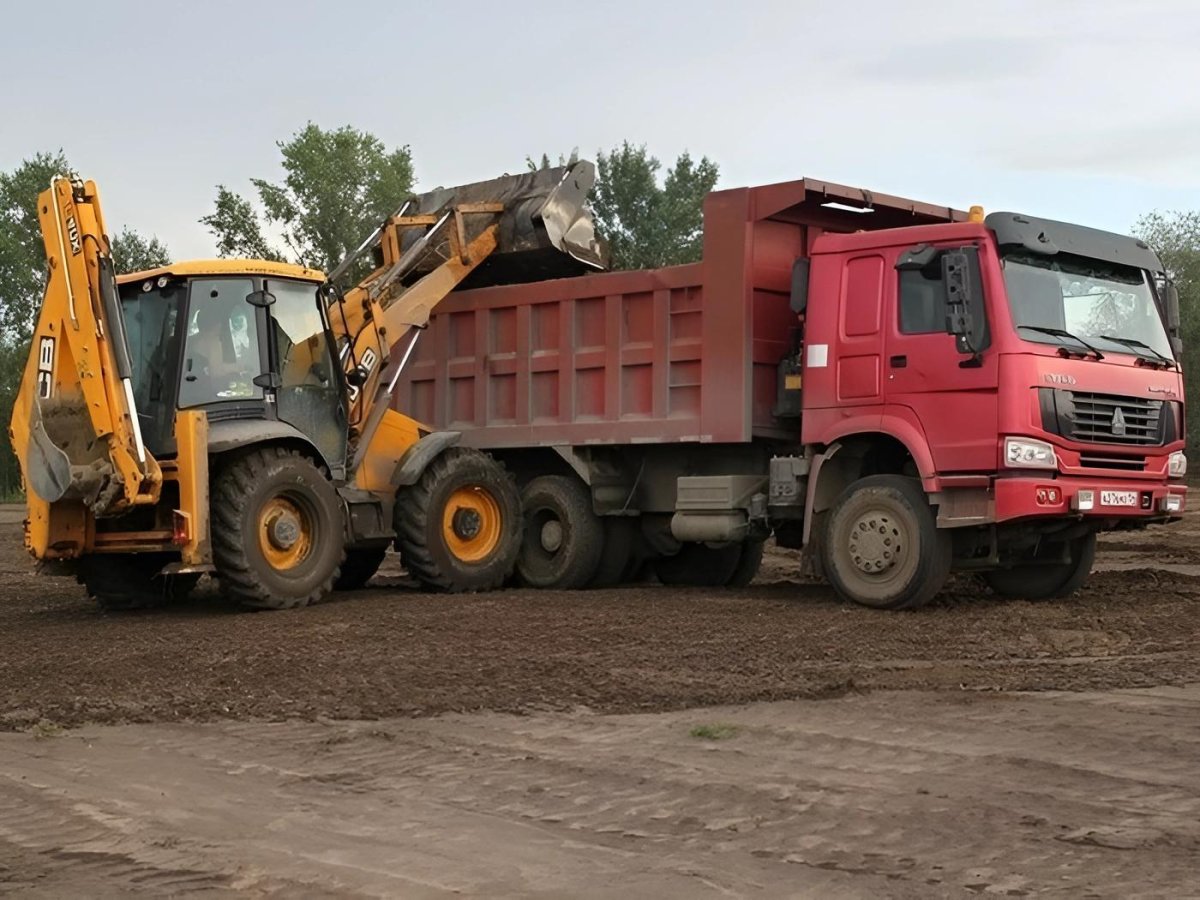 Экскаватор грузит песок в КАМАЗ