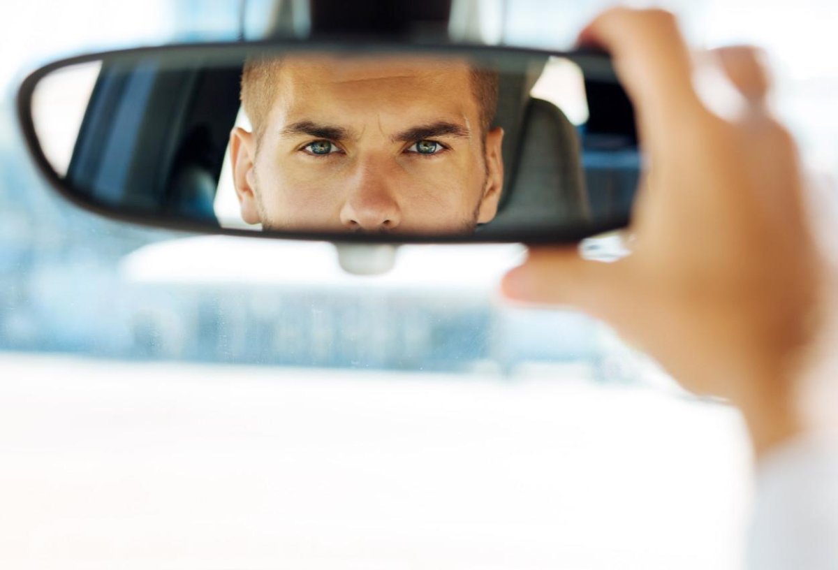 Мужчина смотрит в зеркало заднего вида